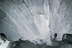 Winter Baikal. Olkhon Island. Ice grotto. Thick blue ice and icicles on the coastal rocks of Olkhon Island in winter