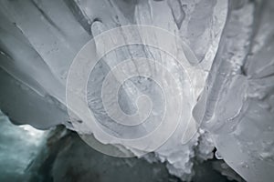 Winter Baikal. Olkhon Island. Ice grotto. Thick blue ice and icicles on the coastal rocks of Olkhon Island in winter