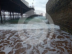 winter beach day outing under pier side sea ocean water waves crashing on shore land