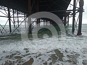 winter beach day outing under pier side sea ocean water waves crashing on shore land