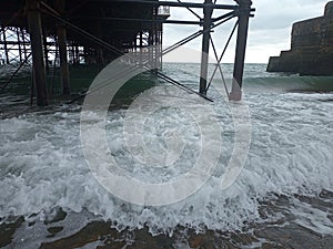 winter beach day outing under pier side sea ocean water waves crashing on shore land