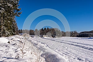Winter beautiful landscape. Ski tracks or trails in the fresh snow. Amazing panoramic view of forest woods against blue sky and wh