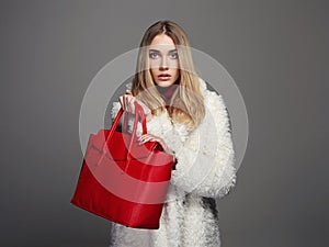 Winter beautiful Woman in Fur Coat. Beauty Fashion Model Girl. luxury stylish blond girl with red Handbag