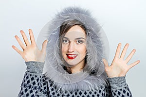 Winter beauty fashion. Beautiful face girl with trendy fur hat gesturing. Emotions. Professional makeup and manicure