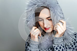 Winter beauty fashion. Beautiful face girl with trendy fur hat gesturing. Emotions. Professional makeup and manicure