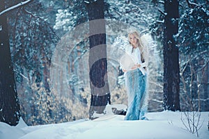 Winter Beauty Woman. Beautiful fashion model girl with snow hairstyle and makeup in the winter forest. Festive makeup and manicure