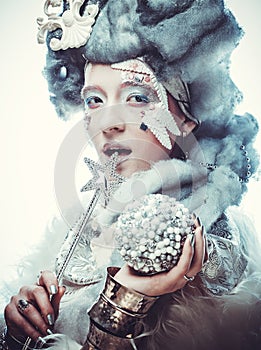 Winter Beauty Woman portrait with silver wig holding magic wand and christmas ball.