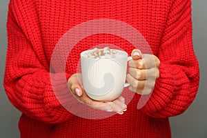 Winter beverage: cup with cocoa or hot chocolate with marshmallows in female hand, cropped image