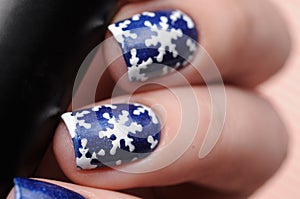 Winter blue manicure with shimmer and snowflakes pattern on red lines candy background