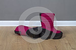 Winter boots snowboots dark pink with black soles on the floor in the room photo