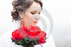 Winter bride holding bouquet of red roses