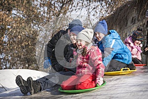 In winter, on a bright sunny day, a crowd of children slides down the hill, clinging to each other