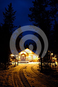 Winter Cabin at Night with Snow and Warm Glowing Lights