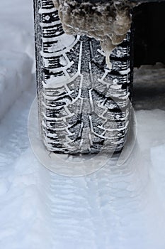 Winter car tire close-up with a trail and a pattern in the snow