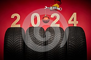 Winter car tires, big wheels service and hand of mechanic man with wrench and christmas ball on red background
