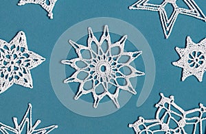 Winter or Christmas background. Crochet snowflakes isolated on light blue. Handmade decorative knitted napkin snowflake