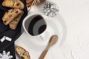 Winter Christmas composition. A cup of coffee on a white table with a black napkin with Italian traditional biscotti cookies and