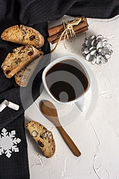 Winter Christmas composition. A cup of coffee on a white table with a black napkin with Italian traditional biscotti cookies and