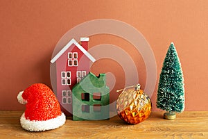 Winter christmas concept. Santa claus hat, house model, bauble, tree on wooden table