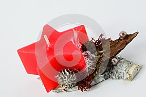 Winter christmas handmade decoration, red star shaped candle on wooden stand with cones and beads