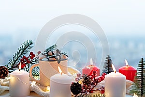 Winter Christmas holidays background with candles; christmas light; Cup of cocoa with marshmallow or hot chocolate near a window