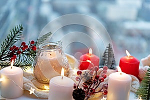 Winter Christmas holidays background with candles; christmas light; Cup of cocoa with marshmallow or hot chocolate near a window