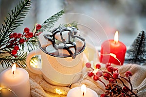 Winter Christmas holidays background with candles; christmas light; Cup of cocoa with marshmallow or hot chocolate near a window