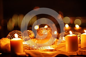 Winter Christmas holidays background with candles, christmas light, toy near a window