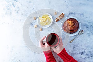 Winter Christmas holidays background with Cup of tea and wool scarf, cinnamon bun roll and snowman