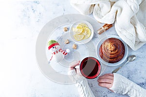 Winter Christmas holidays background with Cup of tea and wool scarf, cinnamon bun roll and snowman