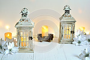 The winter christmas lampions,candles,christmas white flowers on white wooden floor