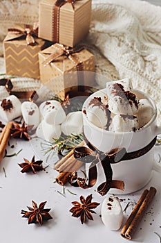 Winter Christmas New Year hot drink. Cup of hot chocolate or cocoa with marshmallow, gift boxes with ribbon, fir branch, star anis