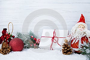 Winter Christmas scene with Christmas tree branches, decorations, toys and Santa Claus on snow and wooden background,