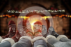 Christmas time, legs in winter socks. Space for your text or decoration. Old fireplace wall background.