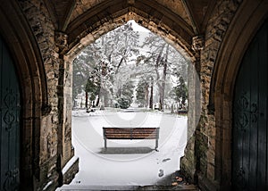 Winter churchyard grave yard with solitary bench in falling snow winter scene archway beautiful and peaceful blanket snowfall Nott