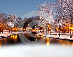 Winter city ,evening park, buildings blurred light ,trees covered by snow, Chon ,snowfall,people walk on snowy street in medieval