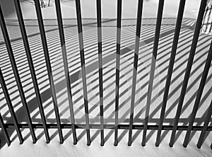 Winter cityscape. Fence and shade from the sun. Black and white photography