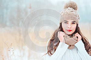 Winter close up portrait of beautiful young woman in knitted hat and sweater walking outdoor