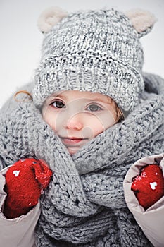 Winter close up vertical portrait of adorable smiling baby girl in grey knitted hat and scarf