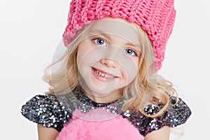 Winter clothes. Portrait of little curly girl in knitted pink winter hat