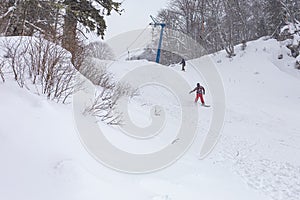 Winter cloudy day, winter sports lovers are engaged in their favorite hobby of conquering the slopes on the mountain slope in the