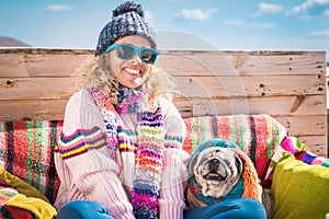 Winter and colorful happy portrait of cheerful beautiful young woman and dog sitting outdoor together - people and animals concept