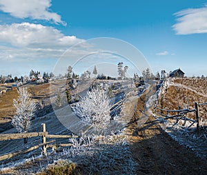 Winter coming. Last days of autumn, morning in mountain countryside peaceful picturesque hoarfrosted scene. Dirty road from hills