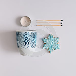 Winter composition made with tea cup, snowflake cookie, matches and candle. Minimal flat lay on white background