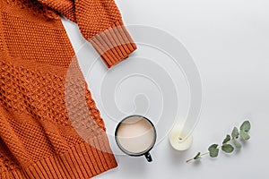Winter composition. Orange sweater, candles and a eucalyptus branch on a white background. Autumn, winter concept. Flat