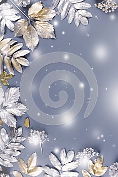 Winter concept flat lay with golden and silver leaves with snow falling. Christmas frame background