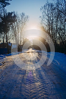 Winter countryside's landscape presented by icy snowy road, trees and houses