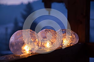 Winter craft: Ice lanterns with flickering fire of a candle