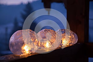 Winter craft: Ice lanterns with flickering fire of a candle photo