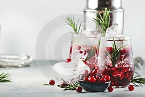 Winter Cranberry cocktail with vodka, ice, juice, rosemary and red berries. Festive long drink. Gray table background with